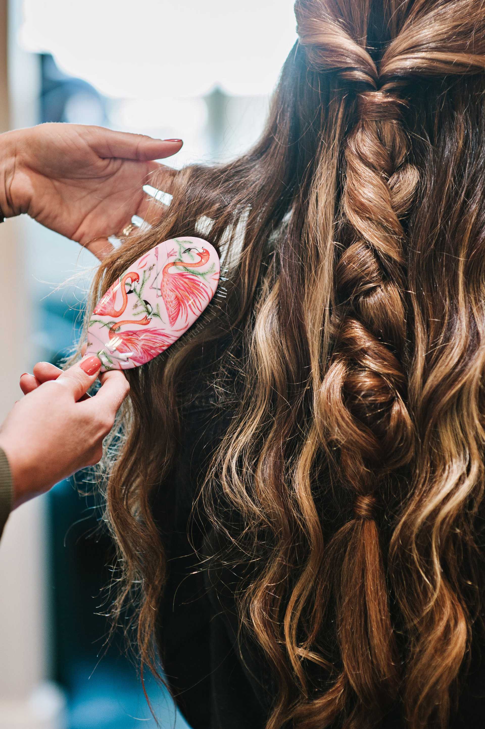 Carefully styled braid being brushed by a person, showing intricate details and waves.