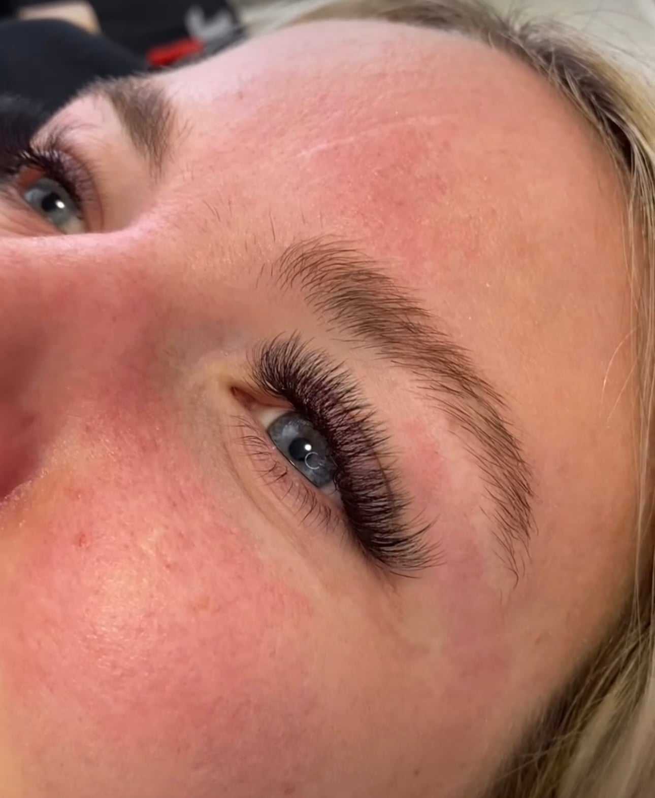 Close-up of a person with long eyelash extensions, showcasing detailed application.