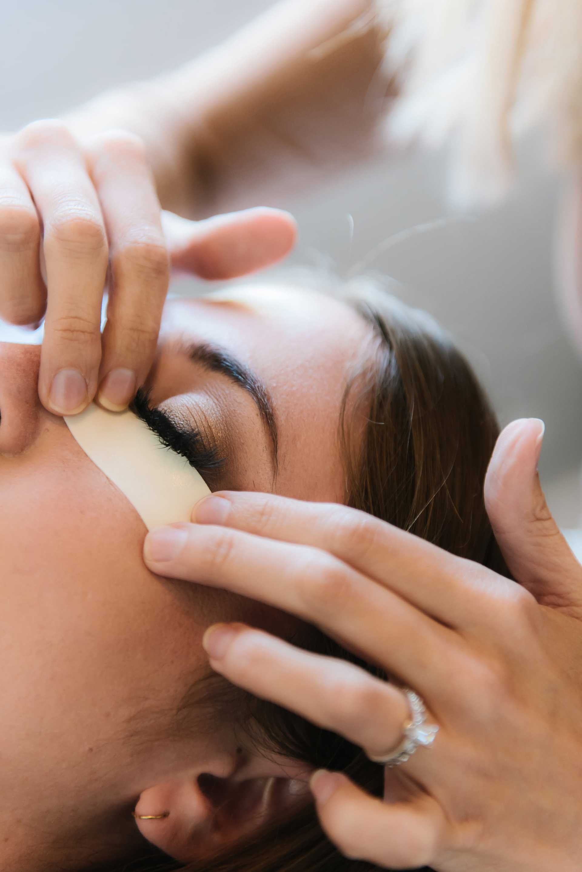 Woman getting an eyebrow treatment with tape applied under her brow.