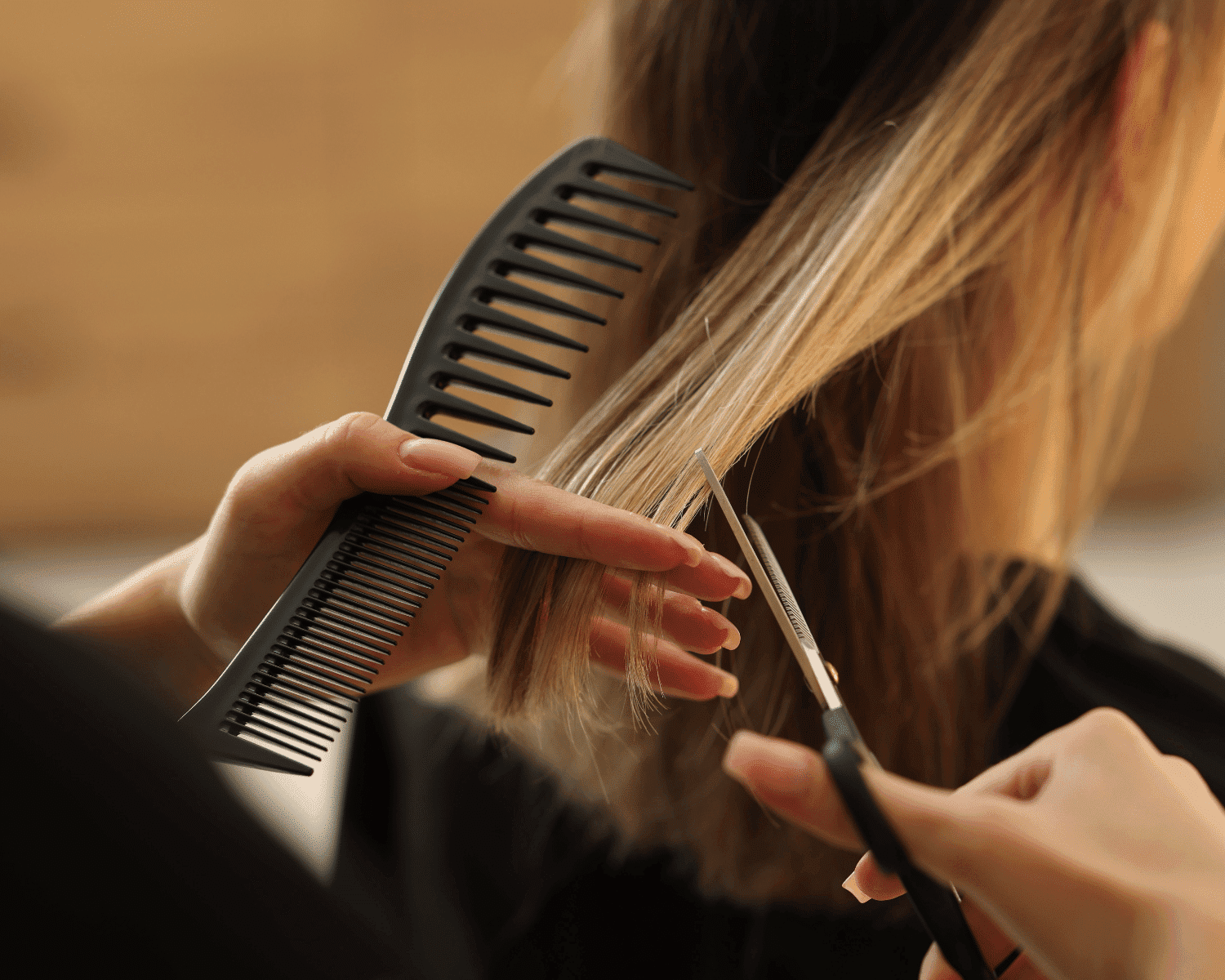 Hair stylist cutting blonde hair with scissors and a comb in a salon setting.