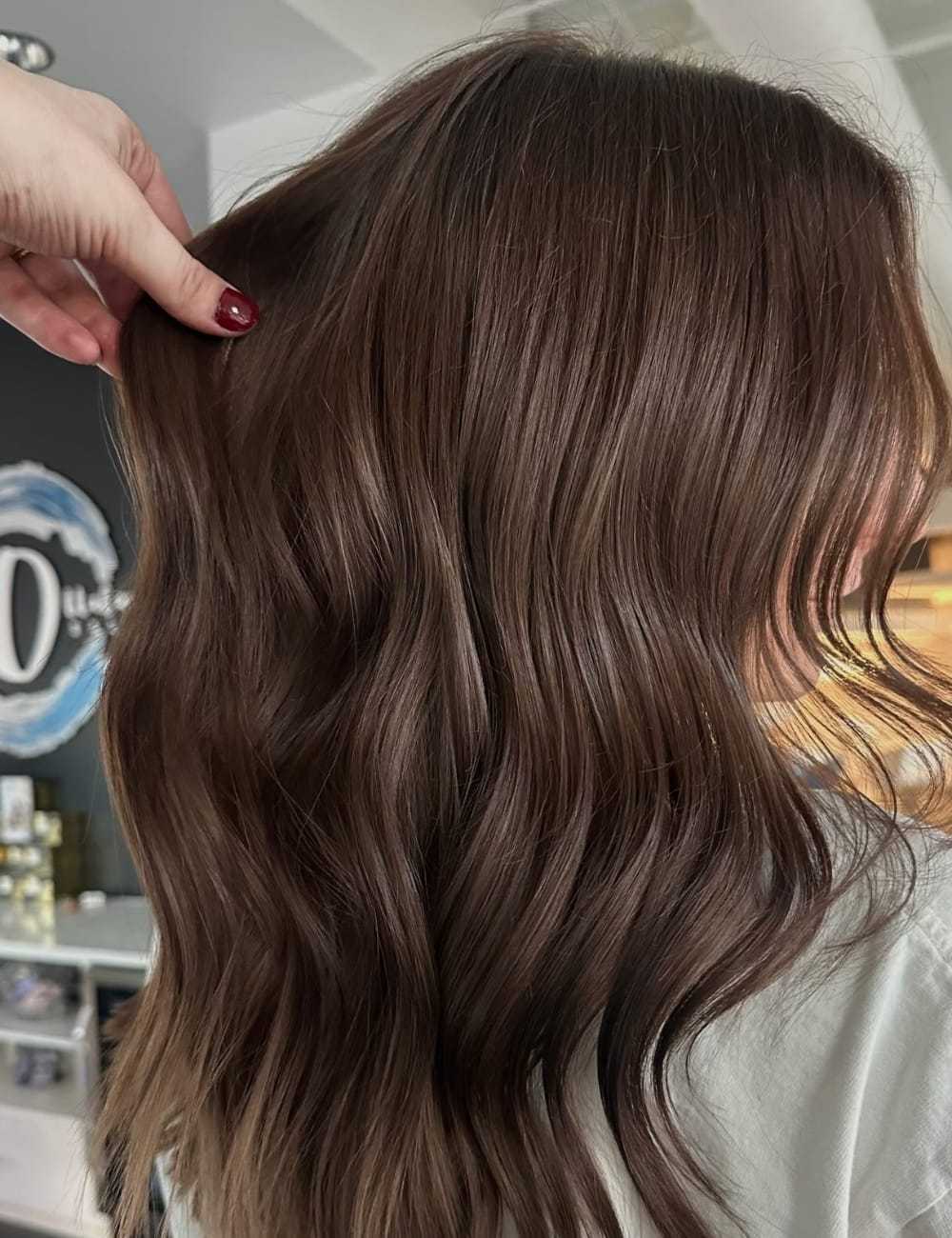 Wavy brown hair with soft sheen being styled in a salon setting.