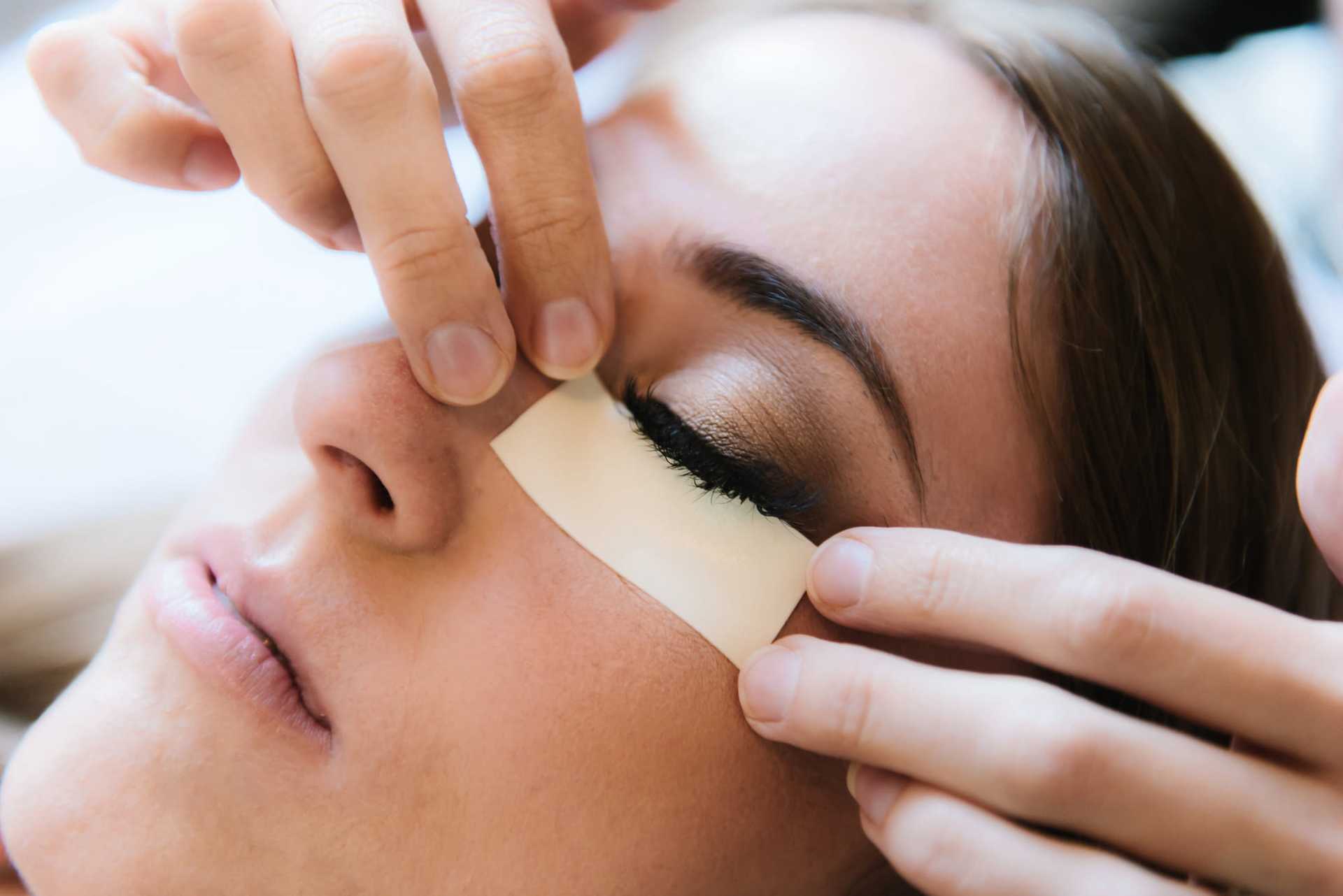 Close-up of a woman receiving an under-eye beauty treatment with adhesive patches.
