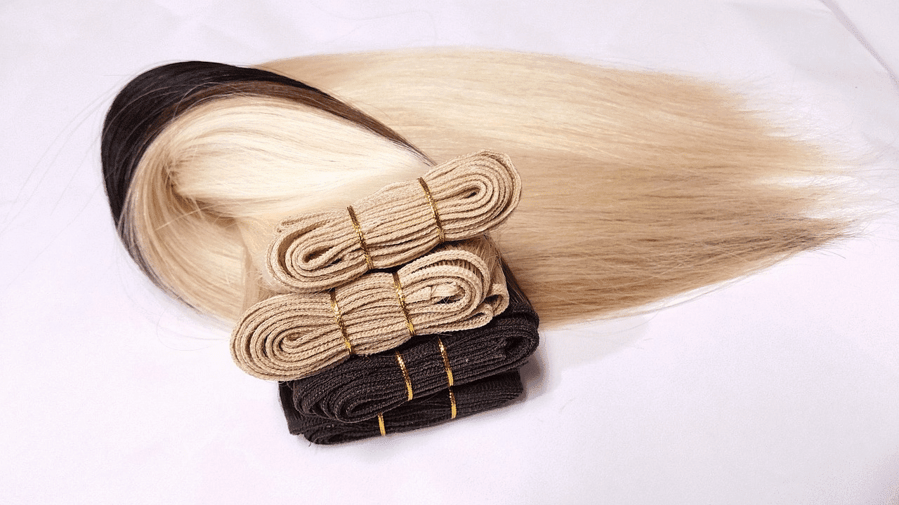 Bundles of black, brown, and blonde hair extensions neatly arranged on a white surface.