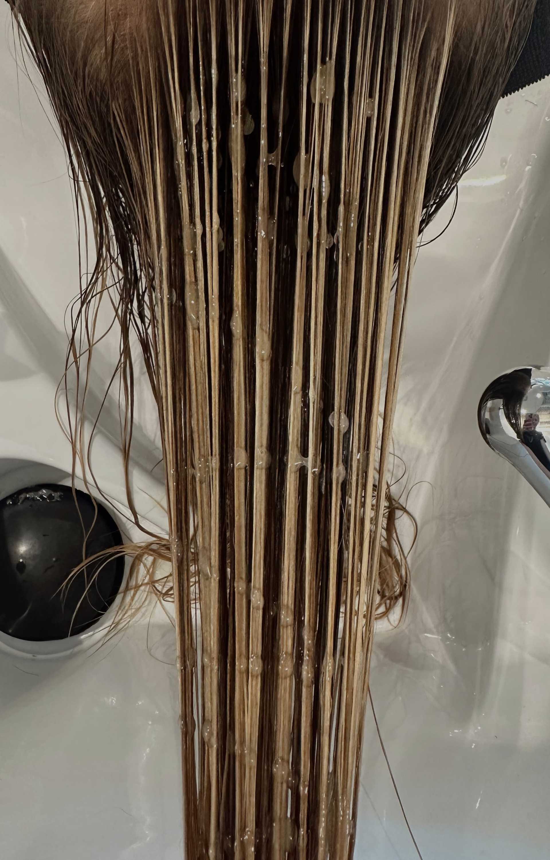 Wet hair with conditioner applied, combed straight down in a salon sink.