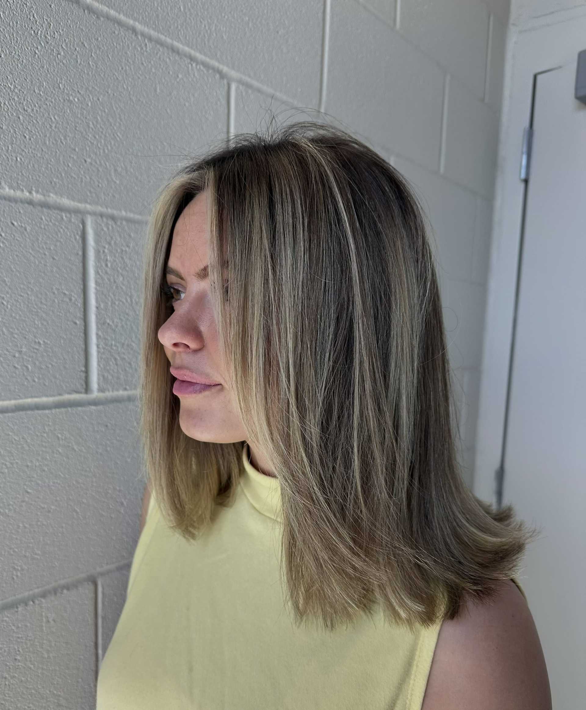 Woman with shoulder-length hair looks confidently to the left. She wears a yellow sleeveless top.