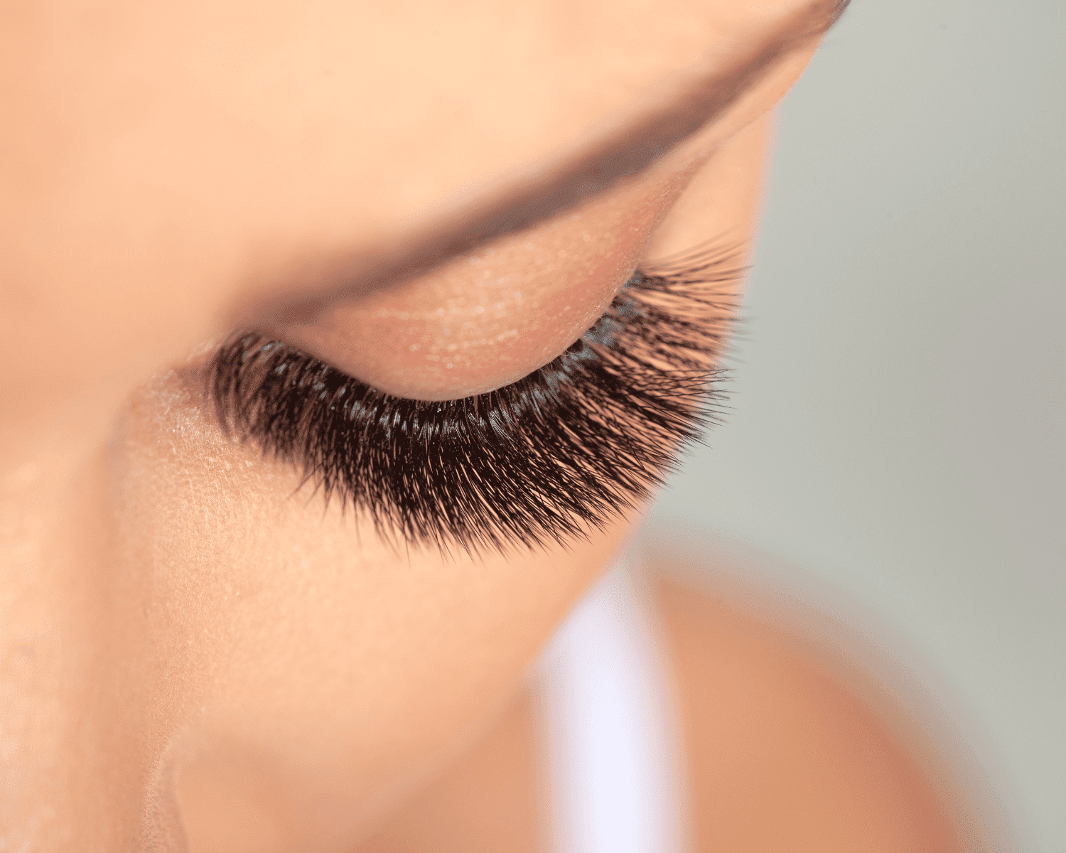 Close-up of a person's eye with thick, long eyelashes, possibly enhanced with extensions.