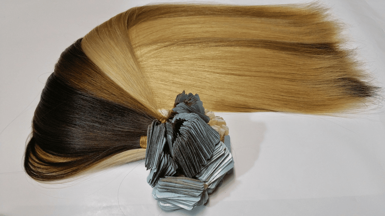Two-toned hair extensions with light brown and blonde colors displayed on a white surface.